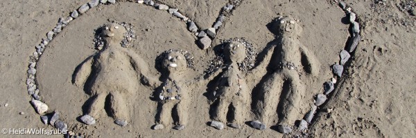 Herz in Sand gemalt mit Vater Mutter Kindern in der Mitte