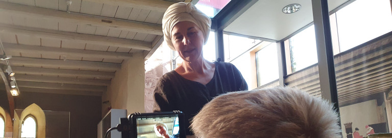 Eine als Magd verkleidete Frau blick in die Kamera