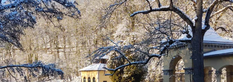 Schneebedeckte Bäume, Pavillon und Fluss im Sonnenschein 