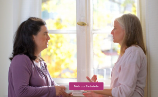 Zwei Frauen vor einem Fenster im Gespräch miteinander