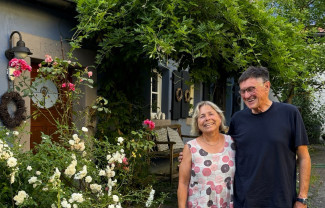 Mann und Frau vor Hauseingang mit Rosen und Goldregen davor